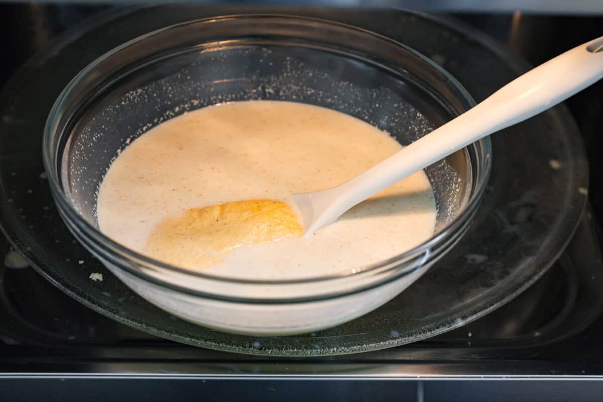Spoon bread is a beloved classic Southern side dish. It’s similar to cornbread but is less sweet and has a softer, almost soufflé-like texture. This unique bread is best enjoyed warm with a dollop of butter, a drizzle of honey or served alongside a hearty bowl of chili. Angle shot of the bowl of milk and cornmeal in a bowl in the microwave.