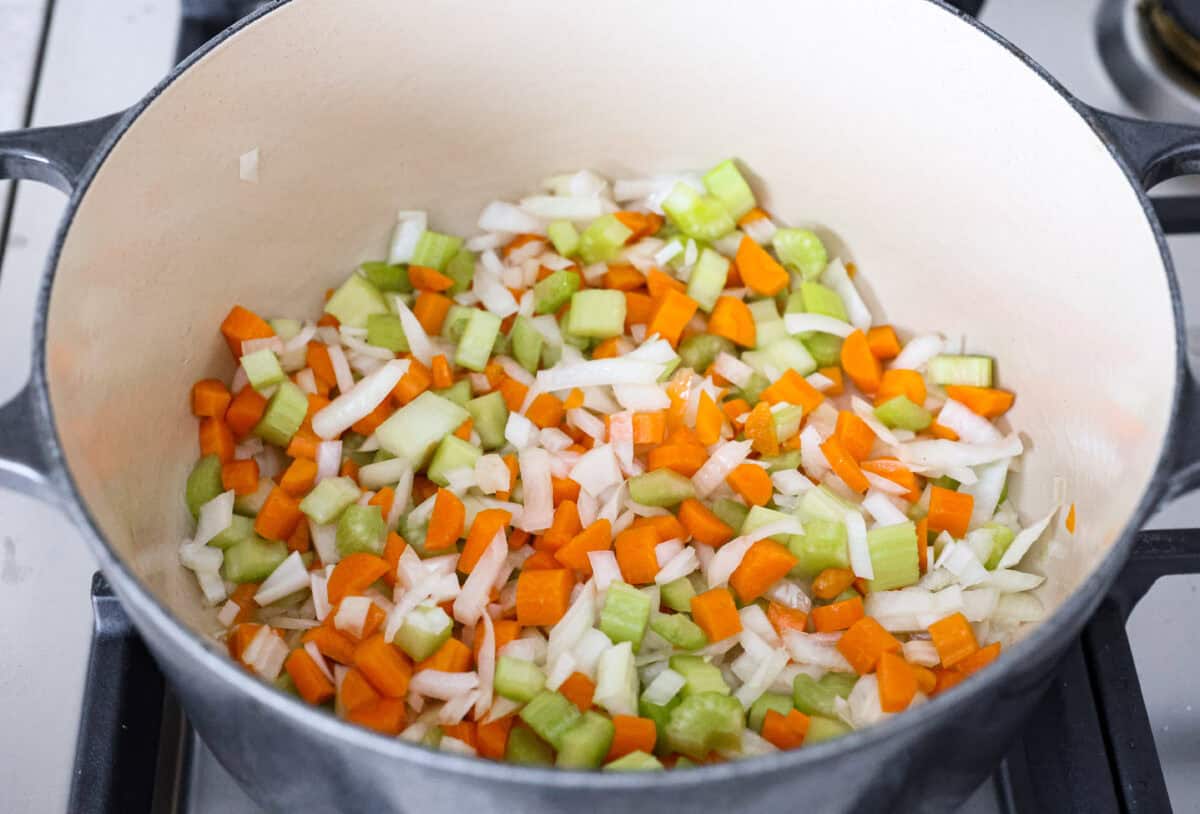 This Detox Cabbage Soup is the perfect way to kick off your New Year's resolutions! After indulging over the holidays, this soup will give you the kick-start you need to feel better. It's loaded with fresh veggies and essential vitamins and is super budget-friendly. Overhead shot of vegetables cooking in olive oil in a pot.