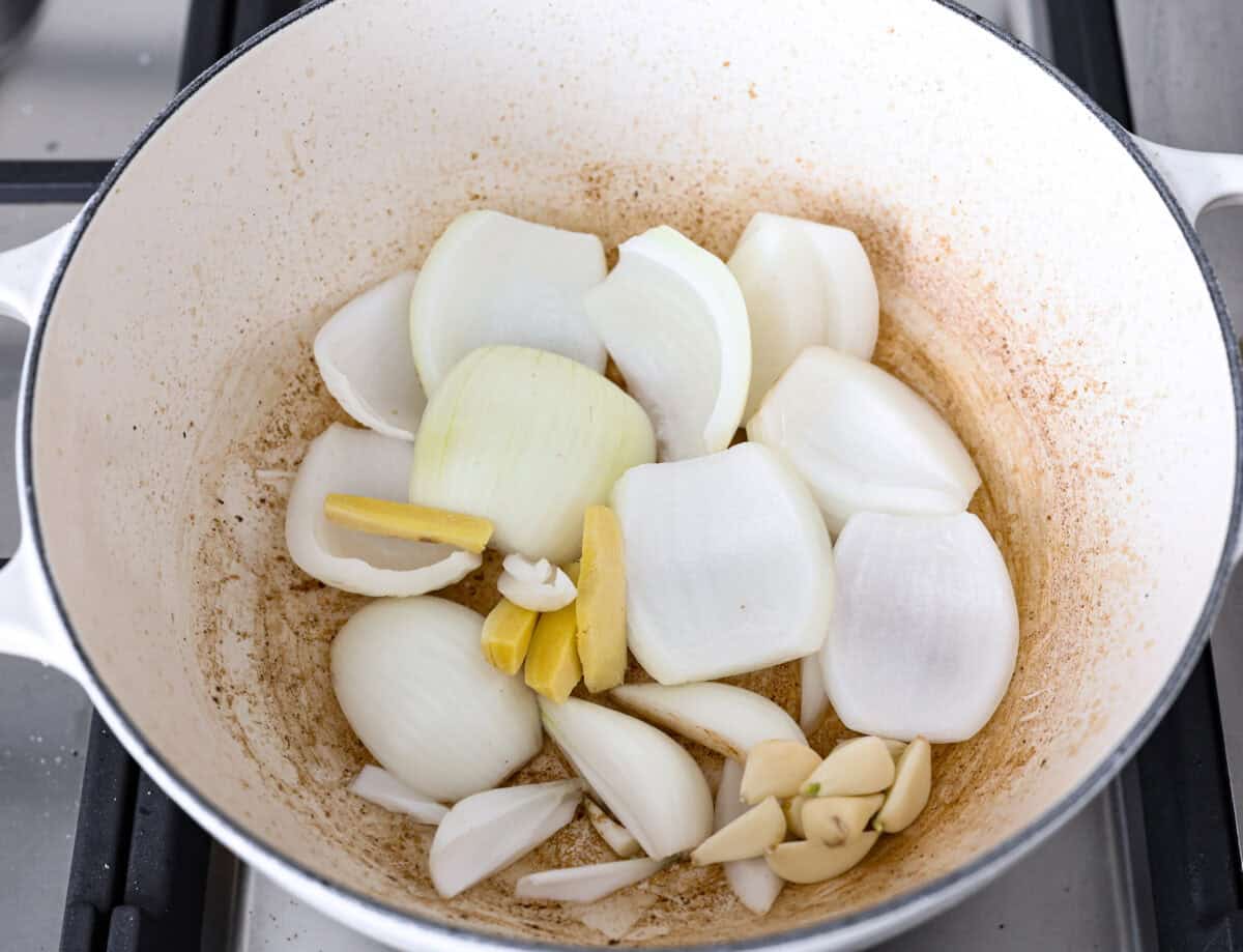 This simplified version of Vietnamese noodle soup brings the comforting flavors you love in Pho but with less effort. For a truly authentic experience, donโt miss out on this detailed recipe! Overhead shot of onions, garlic, ginger, sautรฉing in a pot.