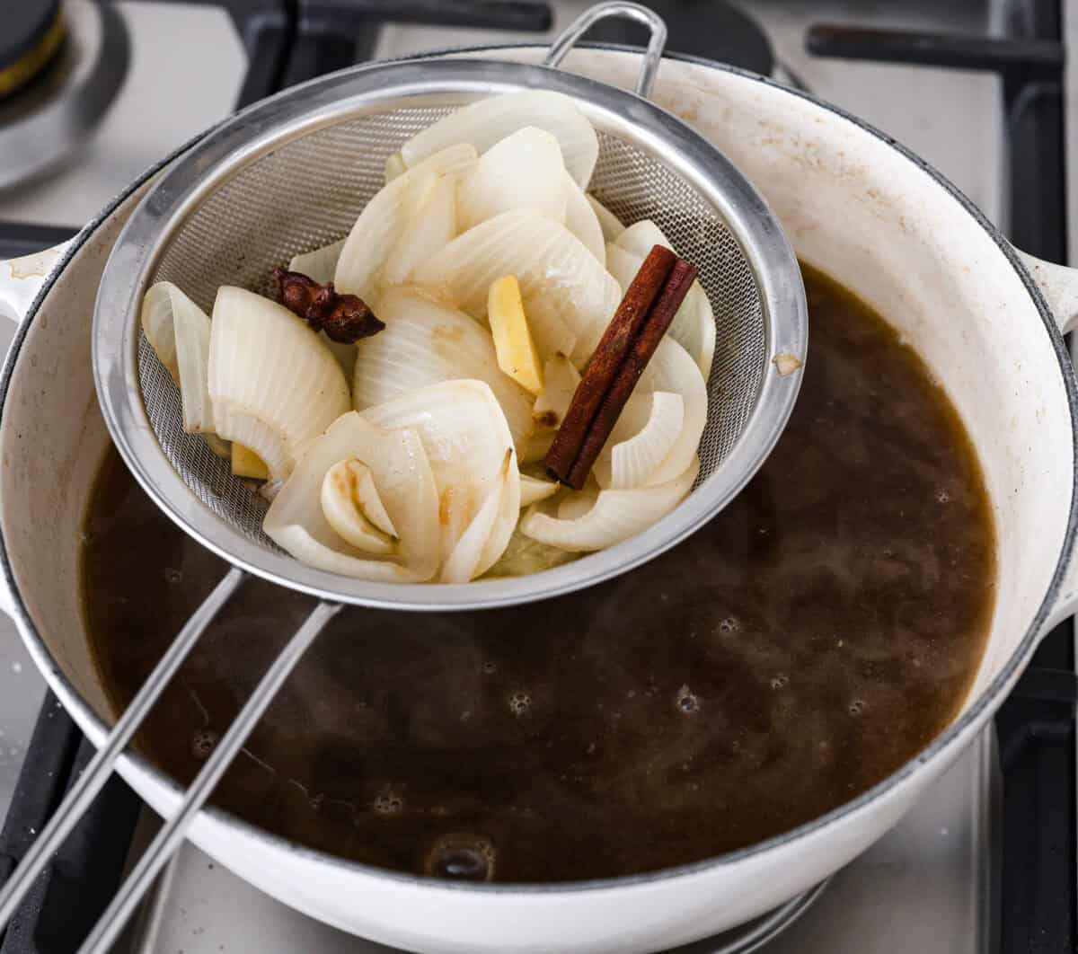 This simplified version of Vietnamese noodle soup brings the comforting flavors you love in Pho but with less effort. For a truly authentic experience, donโt miss out on this detailed recipe! Angle shot of someone lifting the onions and seasonings out of the broth.