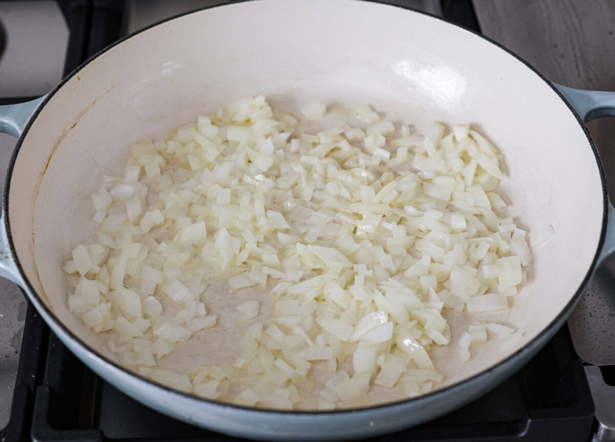 Chicken Pot Pie Pasta is a quick and easy twist on the classic comfort food. This one-pan recipe includes all the creamy, hearty flavors of a traditional chicken pot pie but swaps the pie crust for tender noodles. Itโs a simple, fuss-free meal ready in just 30 minutes! Angle shot of onions sautรฉing in butter in a skillet.