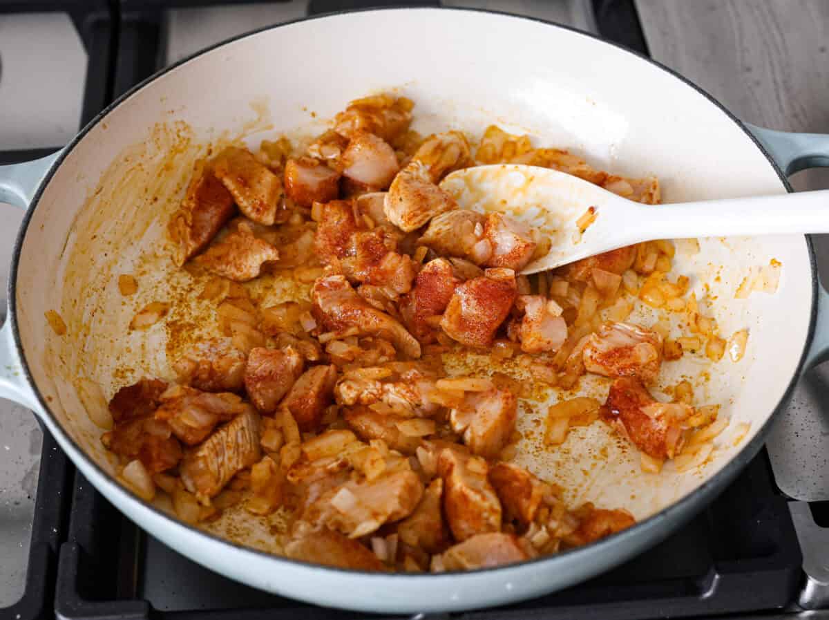 Chicken Pot Pie Pasta is a quick and easy twist on the classic comfort food. This one-pan recipe includes all the creamy, hearty flavors of a traditional chicken pot pie but swaps the pie crust for tender noodles. Itโs a simple, fuss-free meal ready in just 30 minutes! Angle shot of chicken, bullion, garlic powder, and paprika in the skillet with the onions.