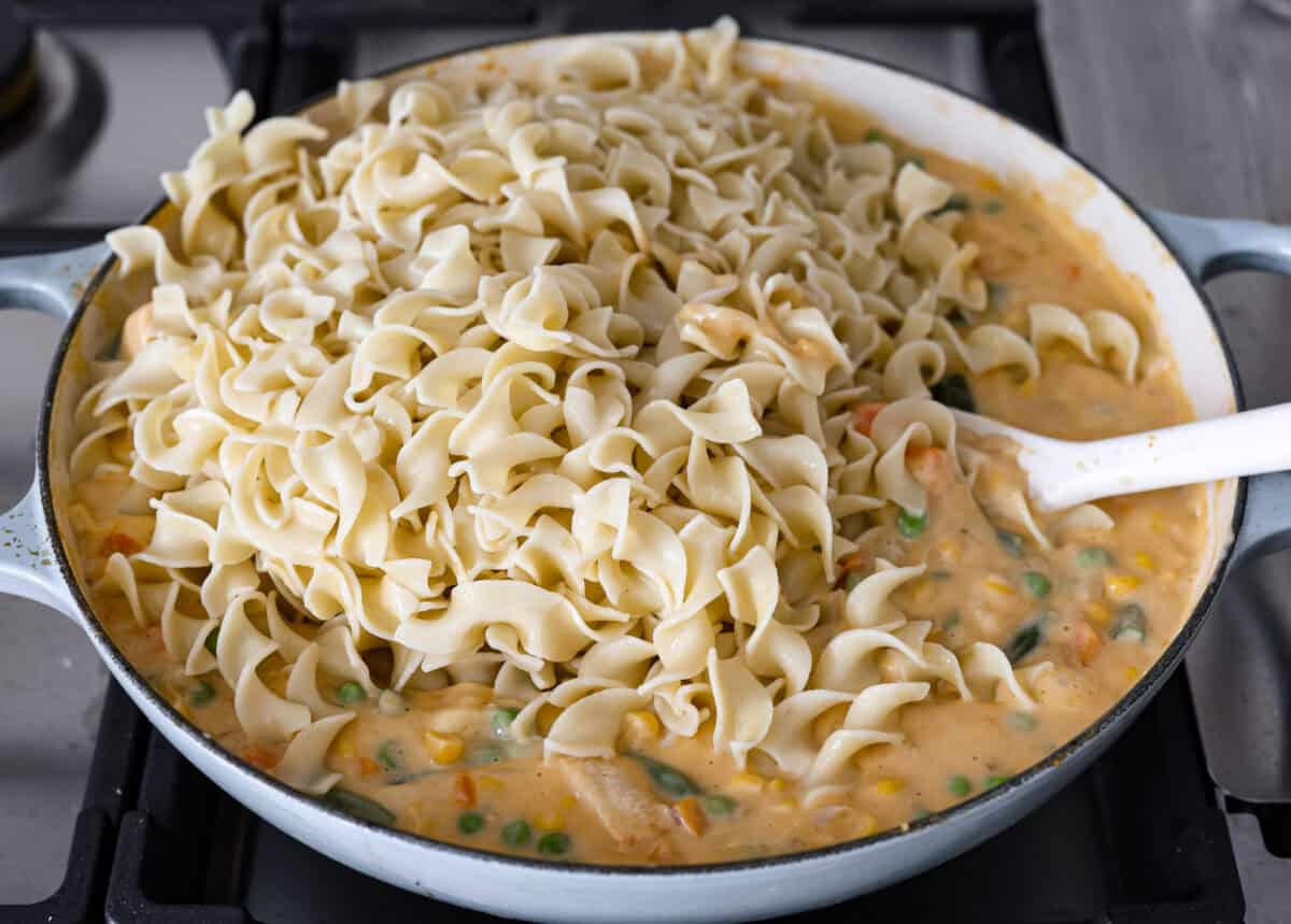 Chicken Pot Pie Pasta is a quick and easy twist on the classic comfort food. This one-pan recipe includes all the creamy, hearty flavors of a traditional chicken pot pie but swaps the pie crust for tender noodles. Itโs a simple, fuss-free meal ready in just 30 minutes! Angle shot of all of the ingredients together in a skillet with the cooked noodles on top.