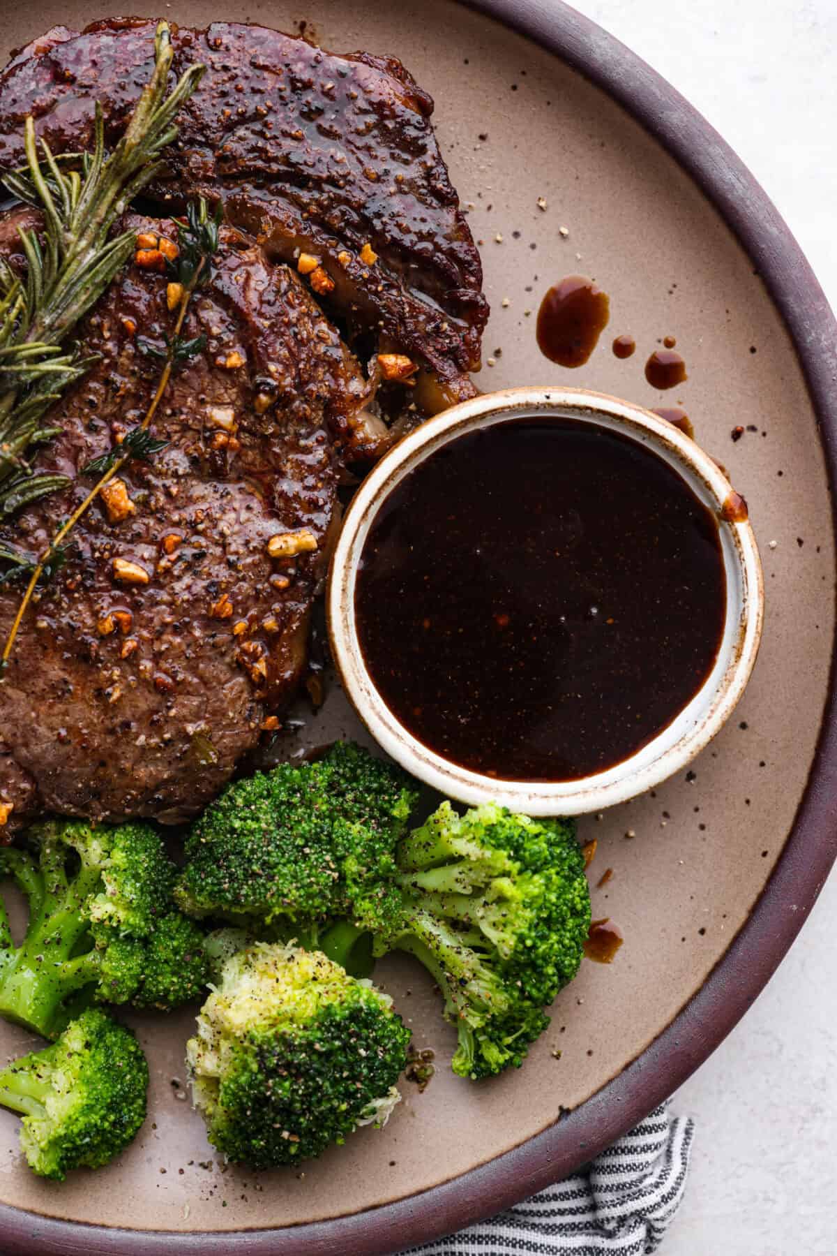 This A-1 copycat homemade steak sauce recipe is slightly sweet with a delicious tang from the vinegar. It's perfect for drizzling over your favorite cut of tender, juicy meat. Overhead shot of a plate with steak next to broccoli, and a small bowl of homemade steak sauce.