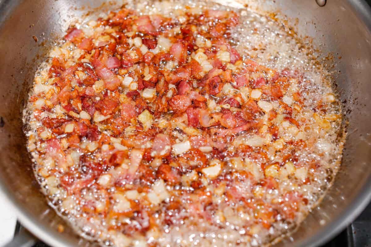 Kickstart your day with this hearty Amish Breakfast Casserole! It's loaded with crispy bacon, tender hash browns, and gooey melted cheese. This dish is a crowd-pleaser thatโs perfect for family breakfasts and holiday mornings! Overhead shot of the garlic cooking with the bacon and onions.
