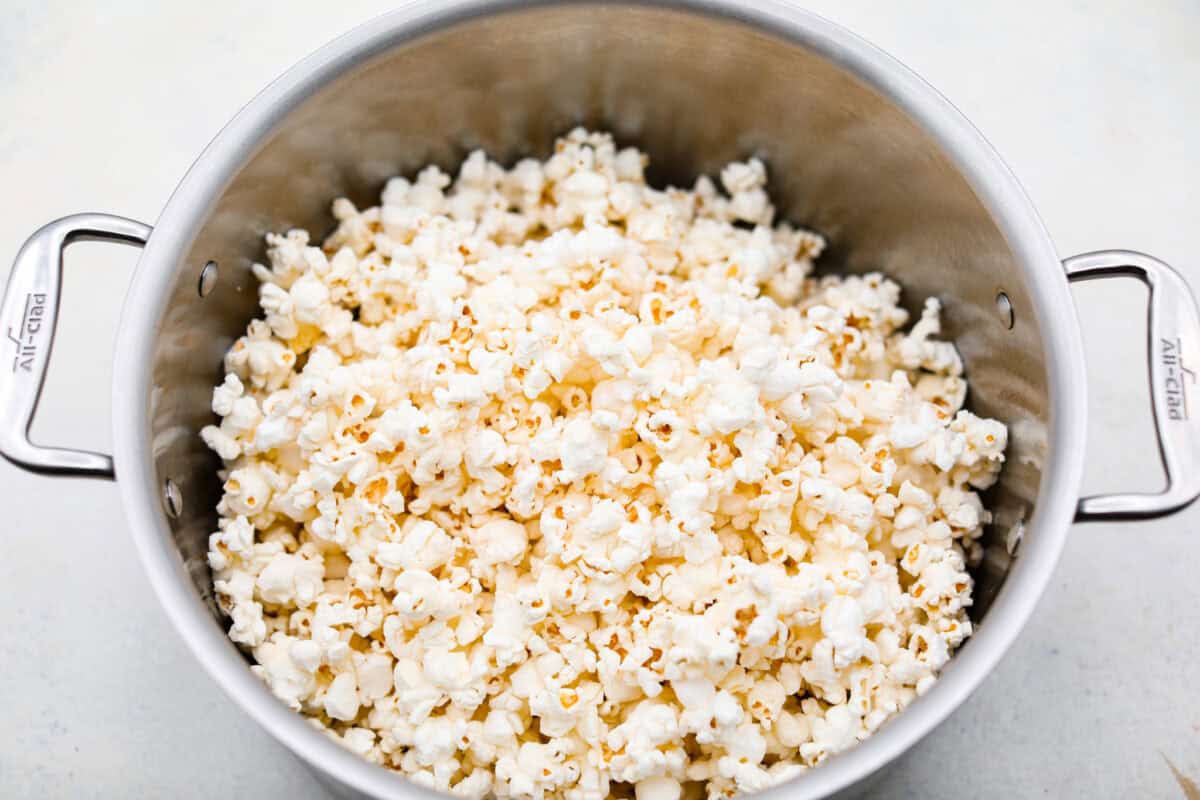 Crunchy and sweet, red hot cinnamon popcorn is like caramel corn with a hint of cinnamon! The butter and sugar mellow out the bold cinnamon flavor of red hots, resulting in a buttery, lightly spiced treat. Itโs less intense than cinnamon bears but just as addictive. Perfect for fans of caramel corn and red hots! Overhead shot of popped popcorn in a large pot.