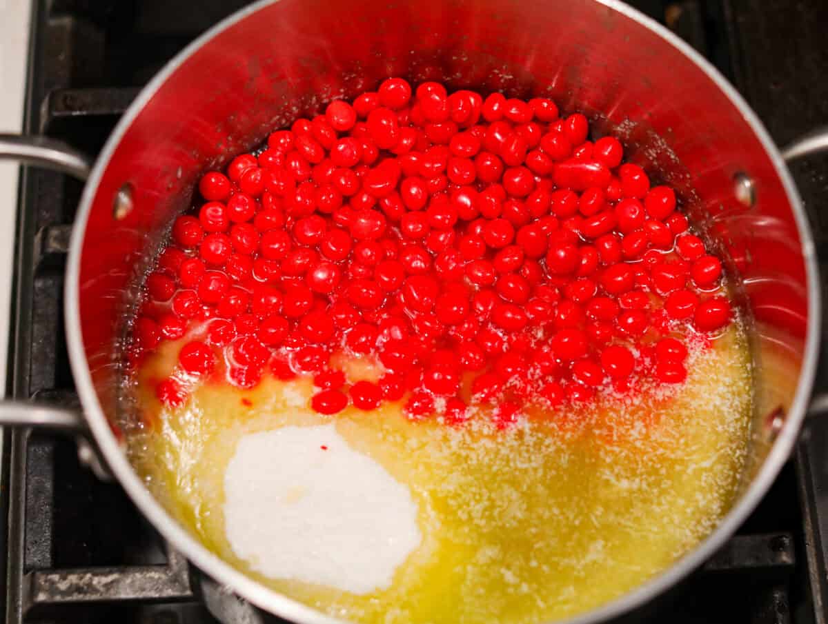 red hots candy Overhead shot of sugar, corn syrup, salt and red hots candies added to the melted butter.