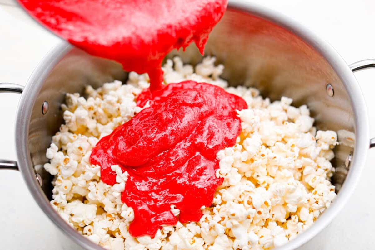 red hots candy Angle shot of someone pouring the candy and butter mixture over the popcorn.