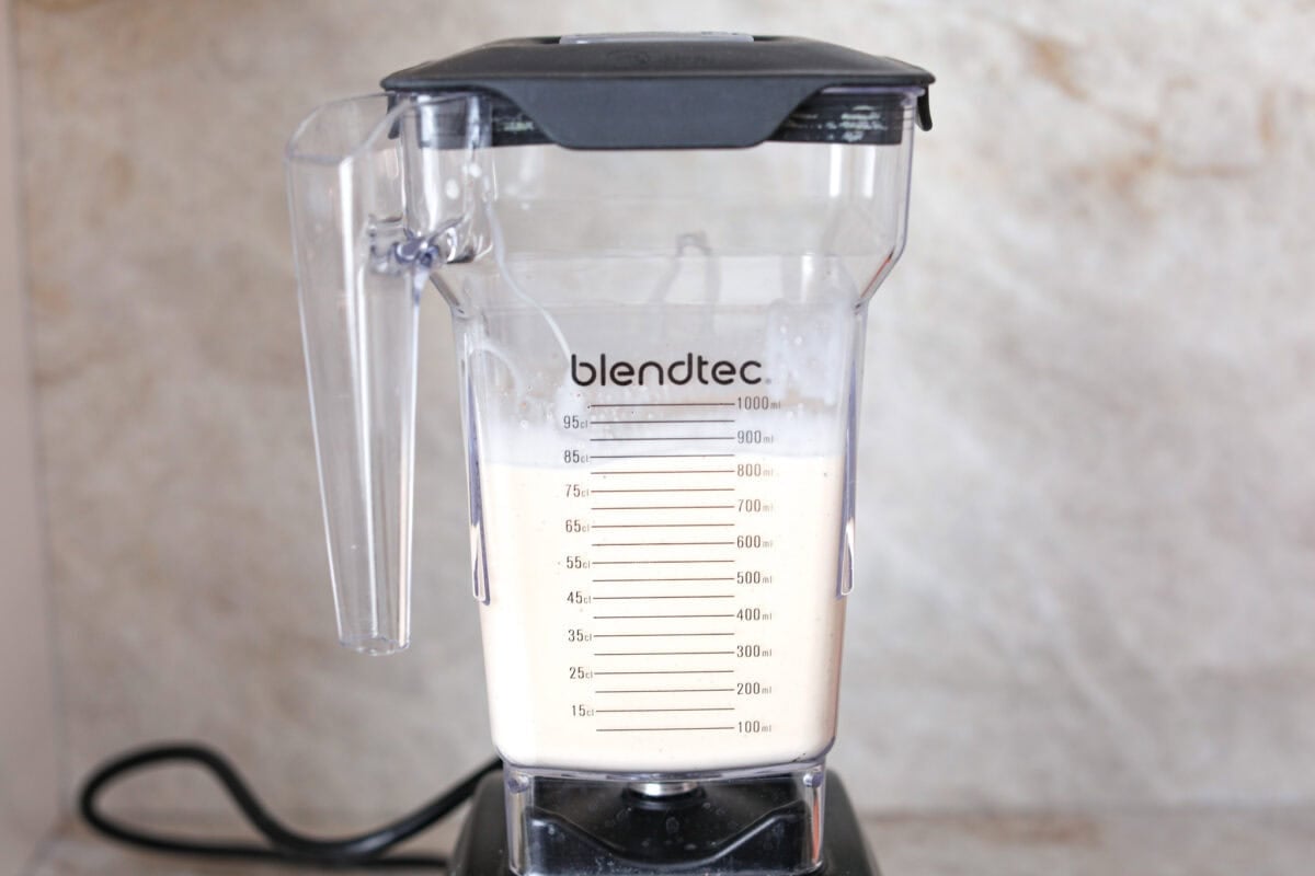 This creamy Eggnog Milkshake is decadent and super flavorful. It takes four simple ingredients and 5 minutes of your time. If you thought you liked eggnog before, you are going to absolutely love it after trying this shake. Side shot of a blender with all of the ingredients blended up inside.