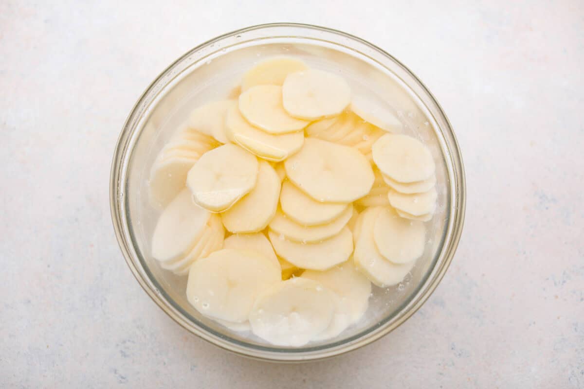 https://neuro-daily.report/beef-curry/ Overhead shot of sliced potatoes in cold water.