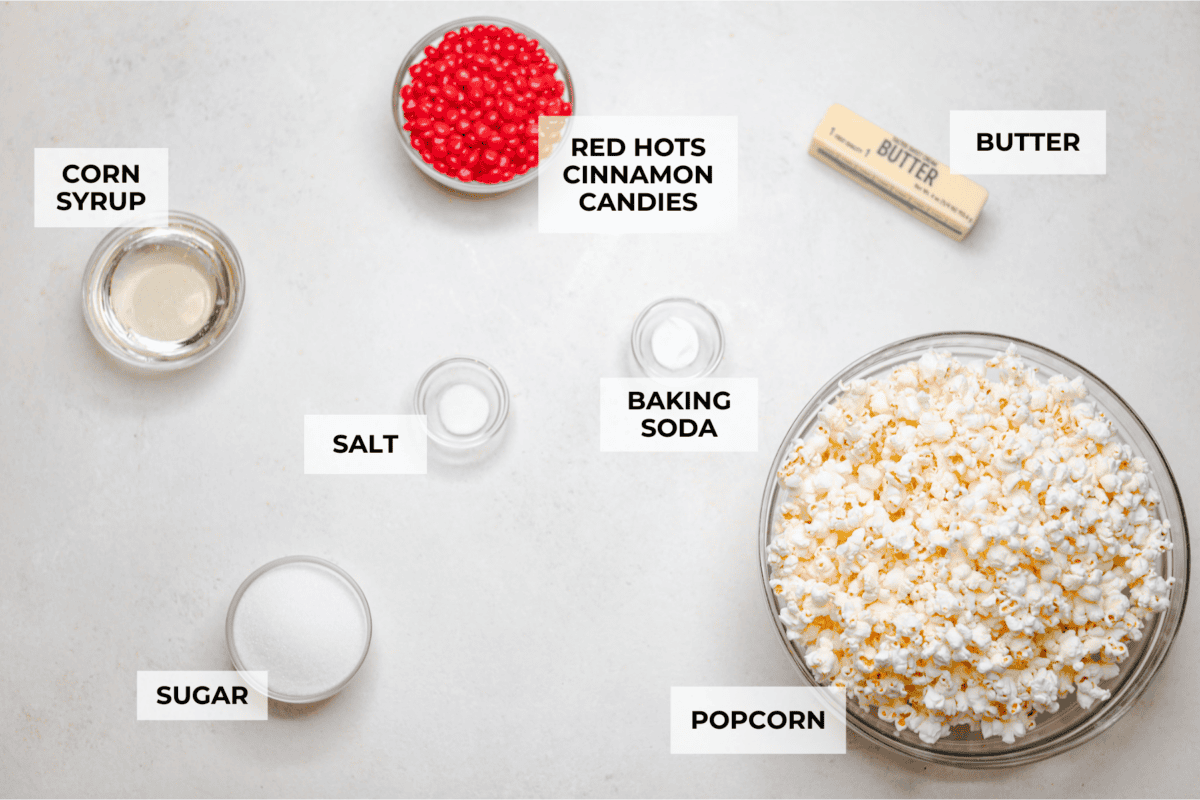 Crunchy and sweet, red hot cinnamon popcorn is like caramel corn with a hint of cinnamon! The butter and sugar mellow out the bold cinnamon flavor of red hots, resulting in a buttery, lightly spiced treat. Itโs less intense than cinnamon bears but just as addictive. Perfect for fans of caramel corn and red hots! Overhead shot of labeled ingredients.