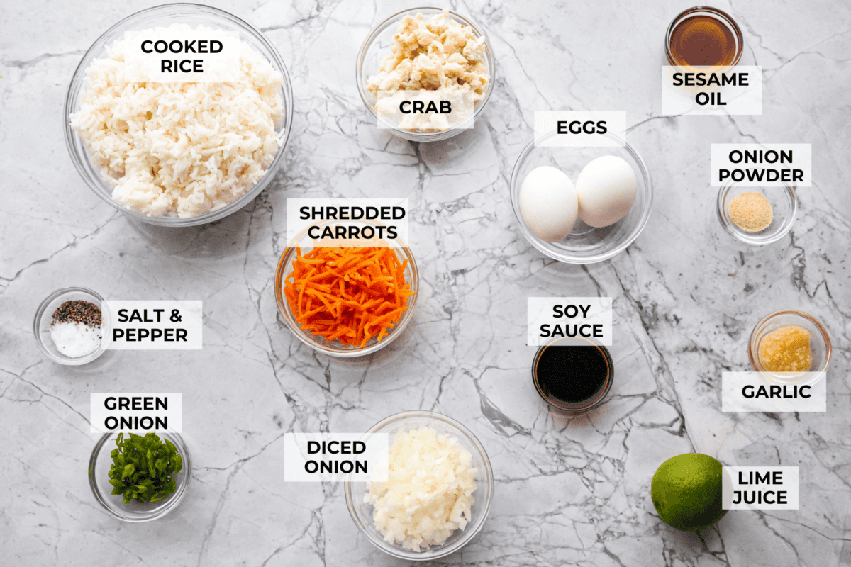 Delicious crab fried rice comes together in just 25 minutes with simple ingredients and tons of flavor! It combines the sweetness of lump crab meat with the savory flavors of classic fried rice for an endlessly satisfying dish that's sure to become a family favorite! Overhead shot of labeled ingredients.