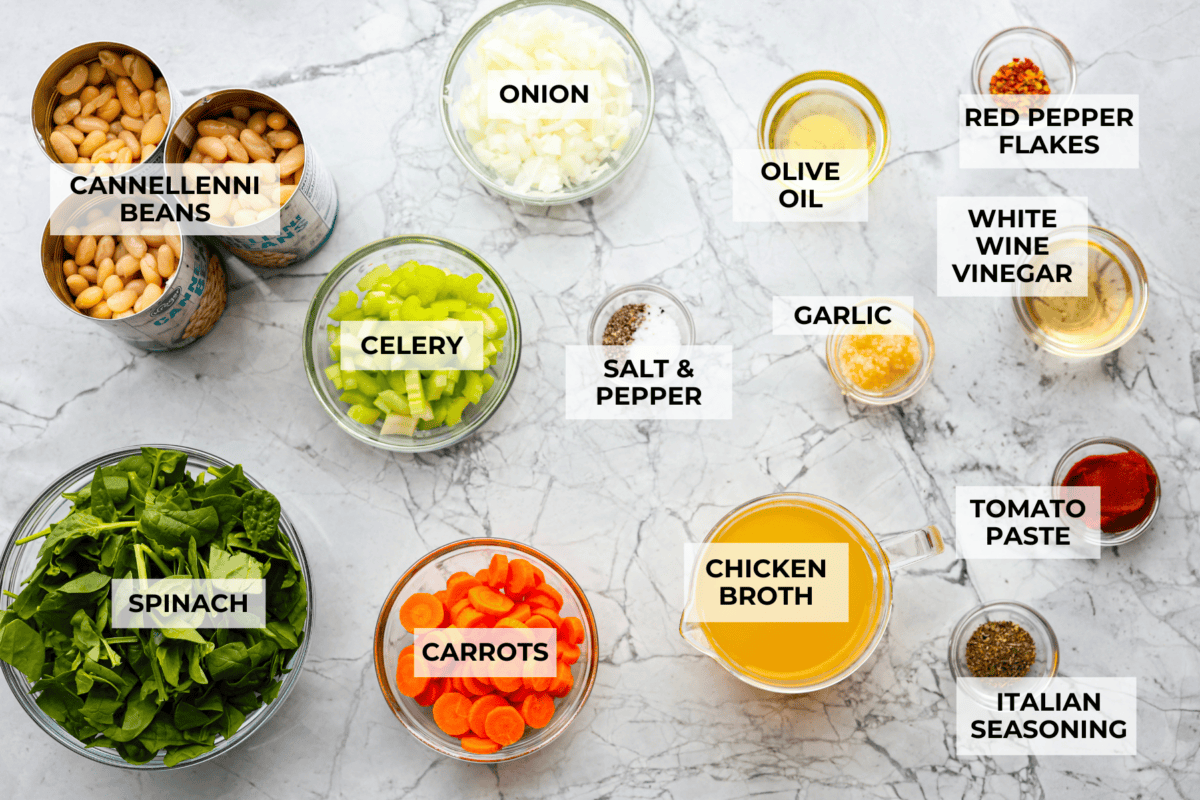 Tuscan white bean soup is like a warm hug in a bowl. Hearty beans and tender vegetables come together to give you a boost of nutrients. This soup is light and fresh tasting, with bright, zesty flavors! Overhead shot of labeled ingredients.
