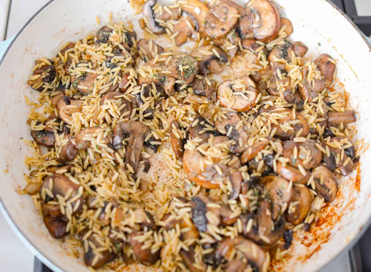 Mushroom orzo is a tasty, comforting side dish! It combines tender orzo pasta with rich, earthy mushrooms in a creamy sauce. It’s easy to make and sure to impress with satisfying texture and savory flavors. Overhead shot of the cooked mushrooms with seasonings and orzo added.