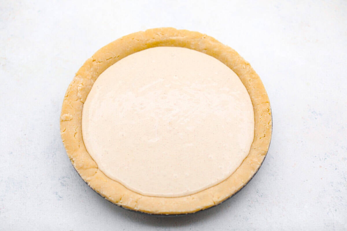 This creamy Ricotta Pie has a milky cinnamon flavor with a hint of lemon. The flavor is incredible, and it's surprisingly light for a cheese-based custard with its buttery shortbread crust. Overhead shot of the prepared pie crust filled with the ricotta filling.