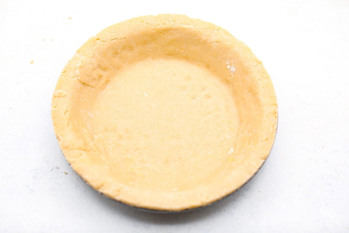 This creamy Ricotta Pie has a milky cinnamon flavor with a hint of lemon. The flavor is incredible, and it's surprisingly light for a cheese-based custard with its buttery shortbread crust. Overhead shot of the pie crust pressed into a pie plate.