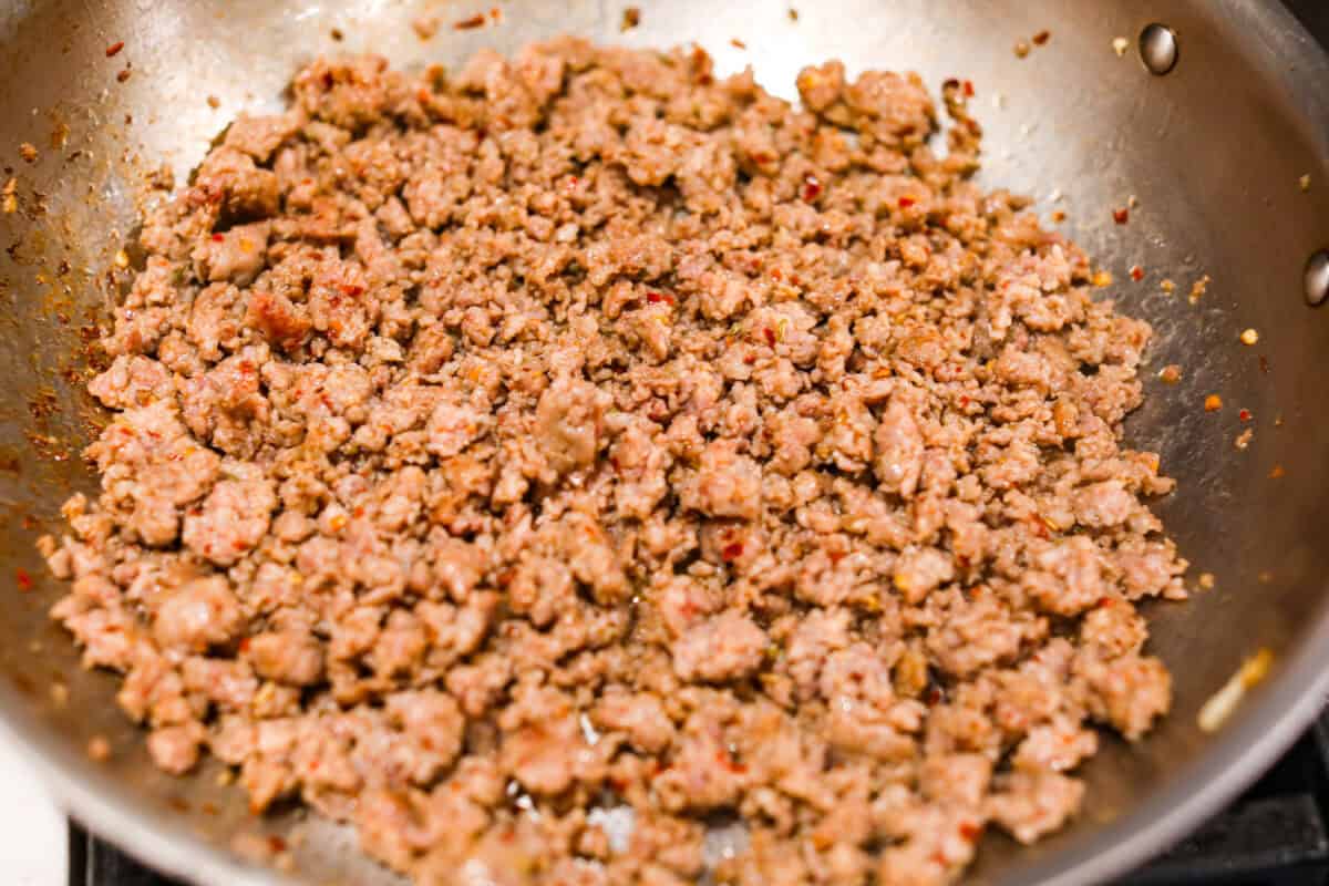 Slow cooker Sunday sauce, also known as "sugo," is a rich, tomato-based ragu that’s a favorite for family dinners. Traditionally, it's simmered low and slow from morning until dinnertime, making it a perfect recipe for the Crockpot. Serve it over pasta with a sprinkle of pecorino romano cheese for an unforgettable meal! Overhead shot of the Italian sausage cooking in a skillet.