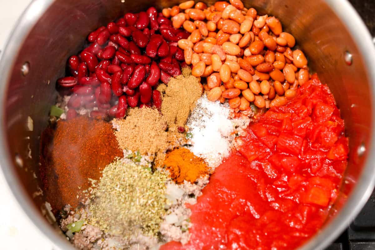 Turkey chili is such a comforting, satisfying meal! Packed with ground turkey, tender vegetables, hearty beans and a blend of bold spices, itโs filled with the most delicious flavor. Great for making ahead and feeding a crowd! Overhead shot of beans, tomatoes and seasonings in the pot with the ground turkey and veggies.