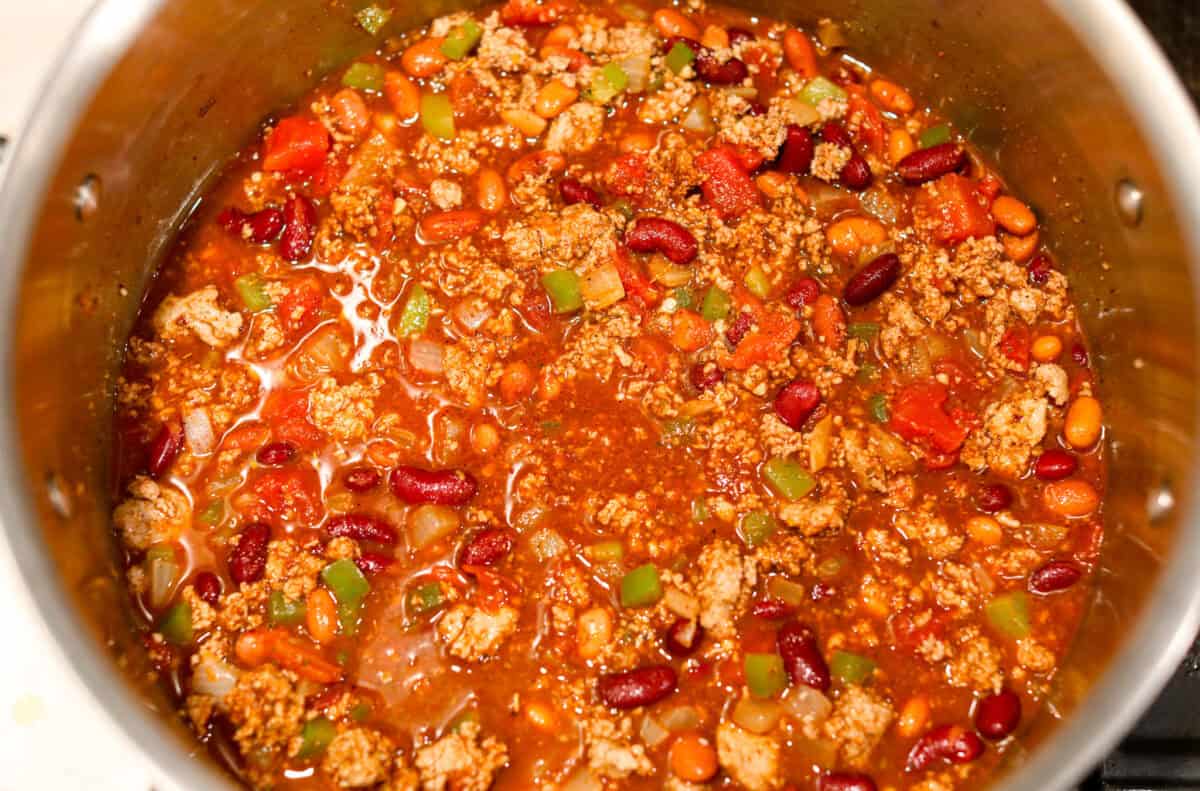Turkey chili is such a comforting, satisfying meal! Packed with ground turkey, tender vegetables, hearty beans and a blend of bold spices, itโs filled with the most delicious flavor. Great for making ahead and feeding a crowd! Overhead shot of all ingredients simmering in a pot.