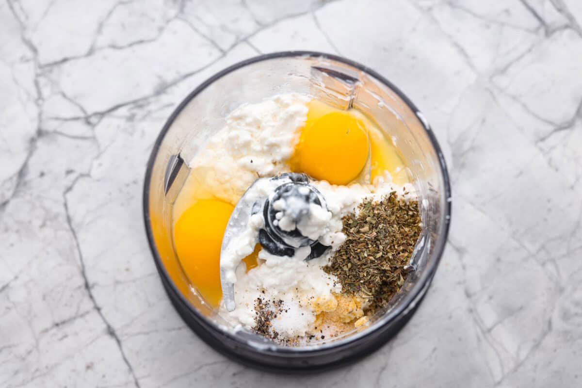 The viralย cottage cheese flatbreadย is a must try! Made with just cottage cheese, eggs and seasonings, itโs packed with almost 20 grams of protein. Use it to make delicious sandwiches or wraps for an easy lunch! Overhead shot of cottage cheese, eggs and seasonings in a food processor.