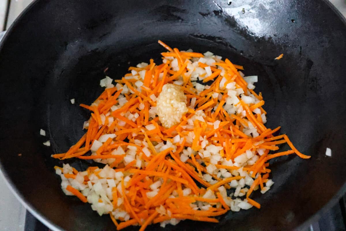 Delicious crab fried rice comes together in just 25 minutes with simple ingredients and tons of flavor! It combines the sweetness of lump crab meat with the savory flavors of classic fried rice for an endlessly satisfying dish that's sure to become a family favorite! Overhead shot of garlic added to the vegetables in the skillet.