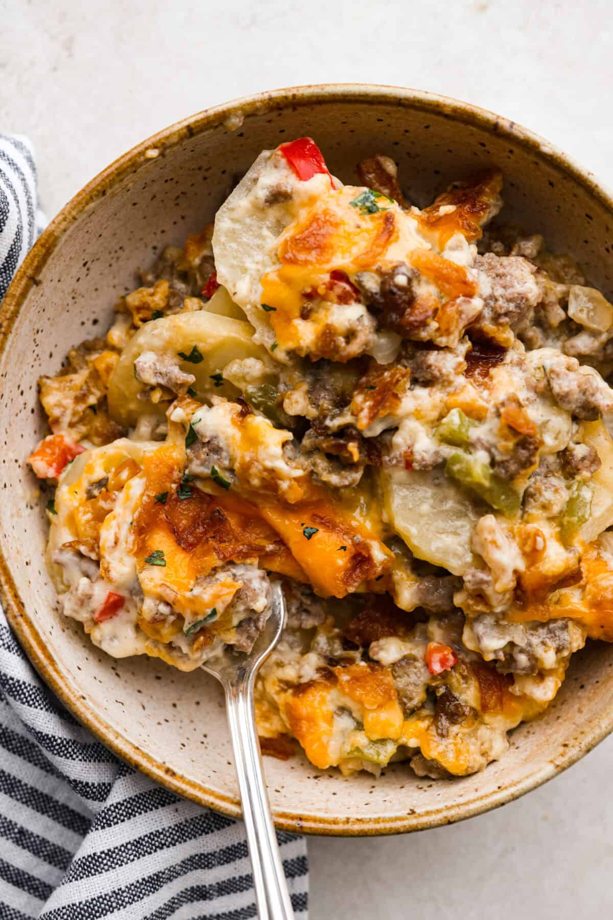 Hobo Casserole is a hearty, beefy, and cheesy dish your whole family will love. It's full of comforting flavors, tender potatoes, creamy sauce, and browned beef. This is a quick and simple recipe that is also a great make-ahead meal! Overhead shot of plated casserole.