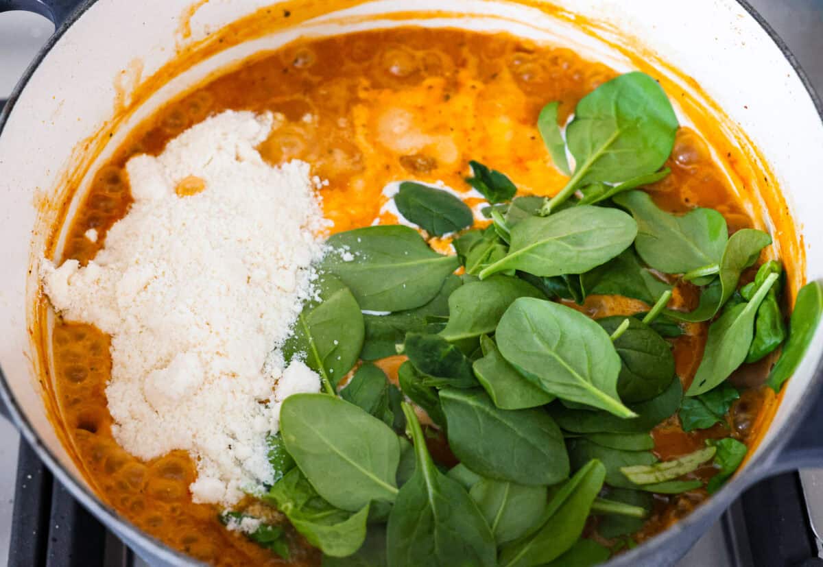 Warm up to this delicious Marry Me sausage orzo soup! It's hearty, super flavorful, and packed with seasoned sausage, tender orzo pasta, and plenty of bold, savory seasonings. Overhead shot of the cream, cheese and spinach added to the rest of the soup.