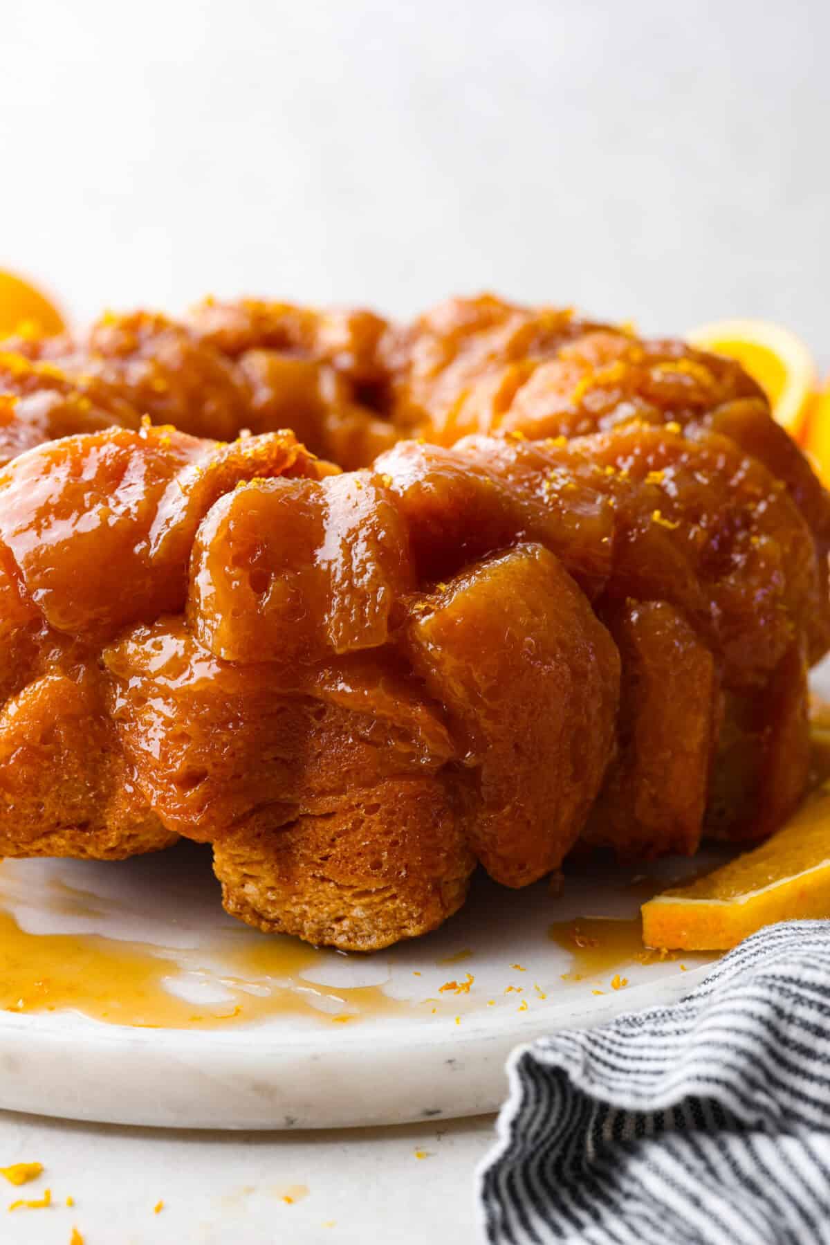 Orange monkey bread is a fun twist on a classic sticky pull-apart bread. It's packed with soft, buttery biscuit pieces, bursts of citrusy orange zest, and a sticky, sweet glaze. Everyone will want to get their hands on this delicious dish! Side shot of orange monkey bread.
