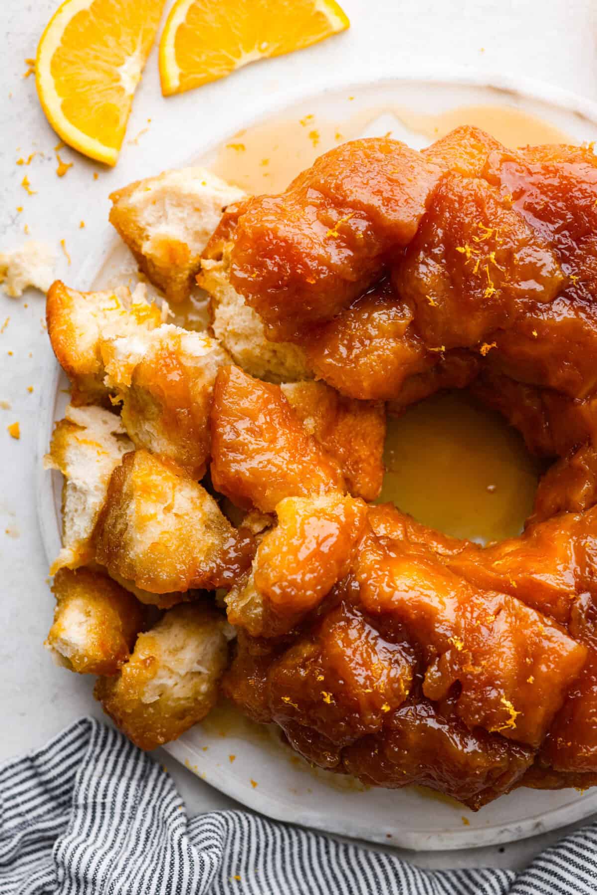 Orange monkey bread is a fun twist on a classic sticky pull-apart bread. It's packed with soft, buttery biscuit pieces, bursts of citrusy orange zest, and a sticky, sweet glaze. Everyone will want to get their hands on this delicious dish! Overhead shot of orange monkey bread.
