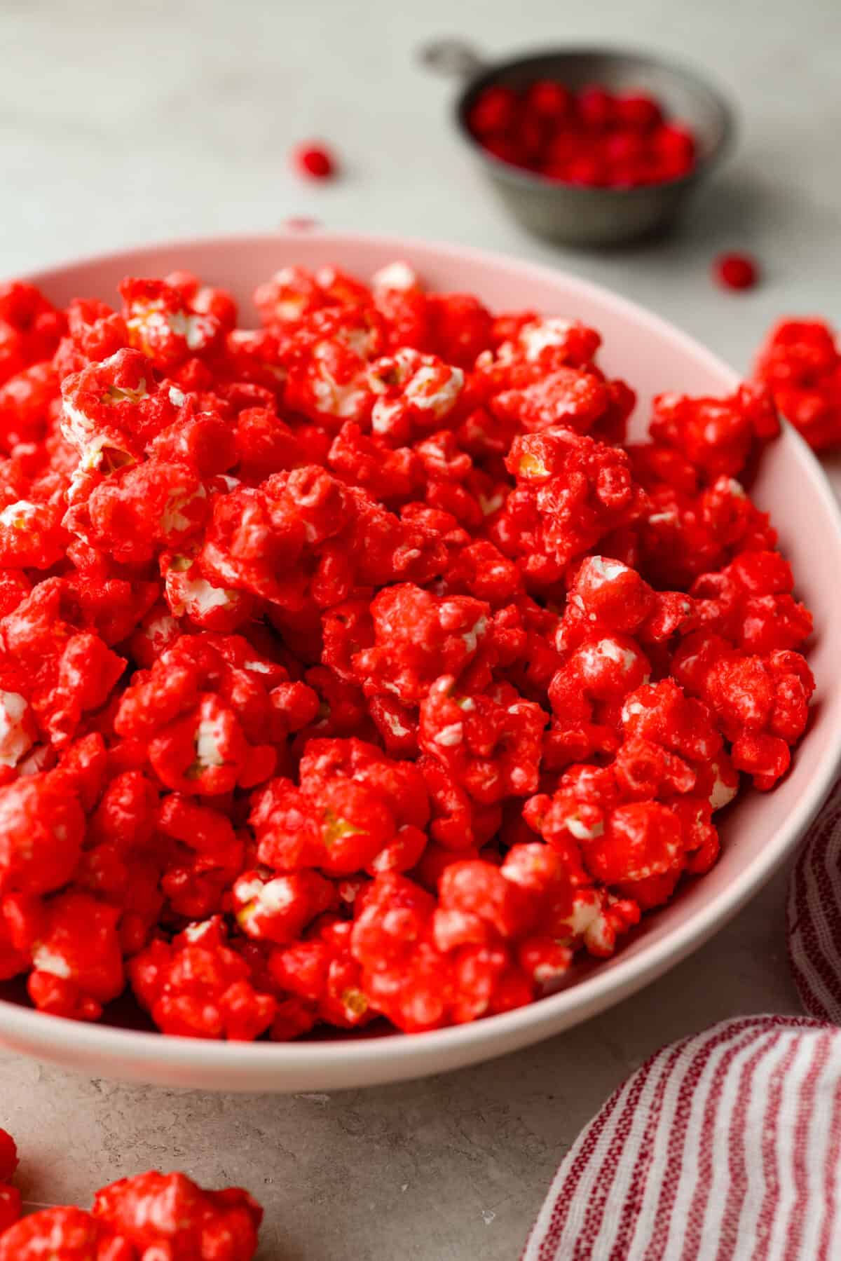 Crunchy and sweet, red hot cinnamon popcorn is like caramel corn with a hint of cinnamon! The butter and sugar mellow out the bold cinnamon flavor of red hots, resulting in a buttery, lightly spiced treat. Itโs less intense than cinnamon bears but just as addictive. Perfect for fans of caramel corn and red hots! Angle shot of red hot cinnamon popcorn in a bowl.