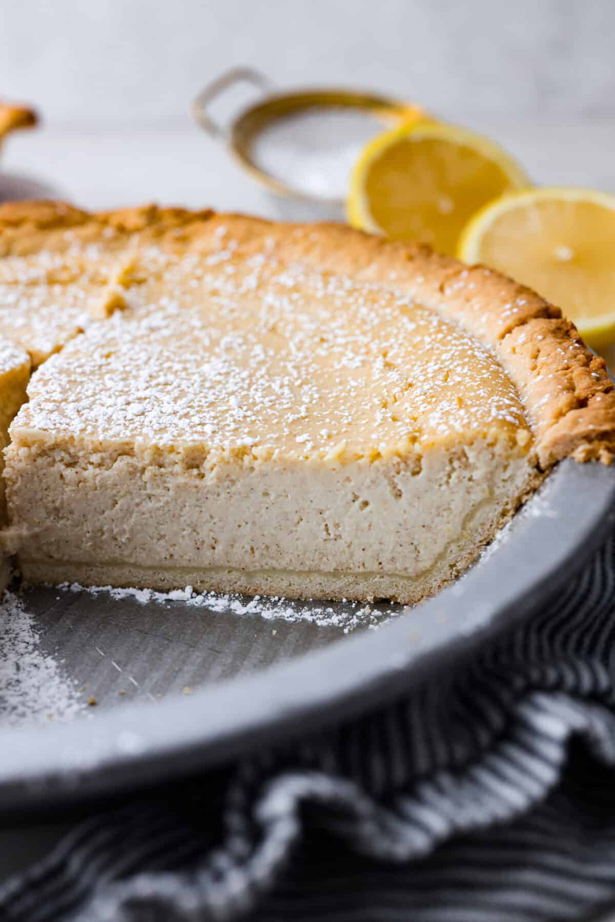 This creamy Ricotta Pie has a milky cinnamon flavor with a hint of lemon. The flavor is incredible, and it's surprisingly light for a cheese-based custard with its buttery shortbread crust. Close up shot of the ricotta pie with a piece taken out.