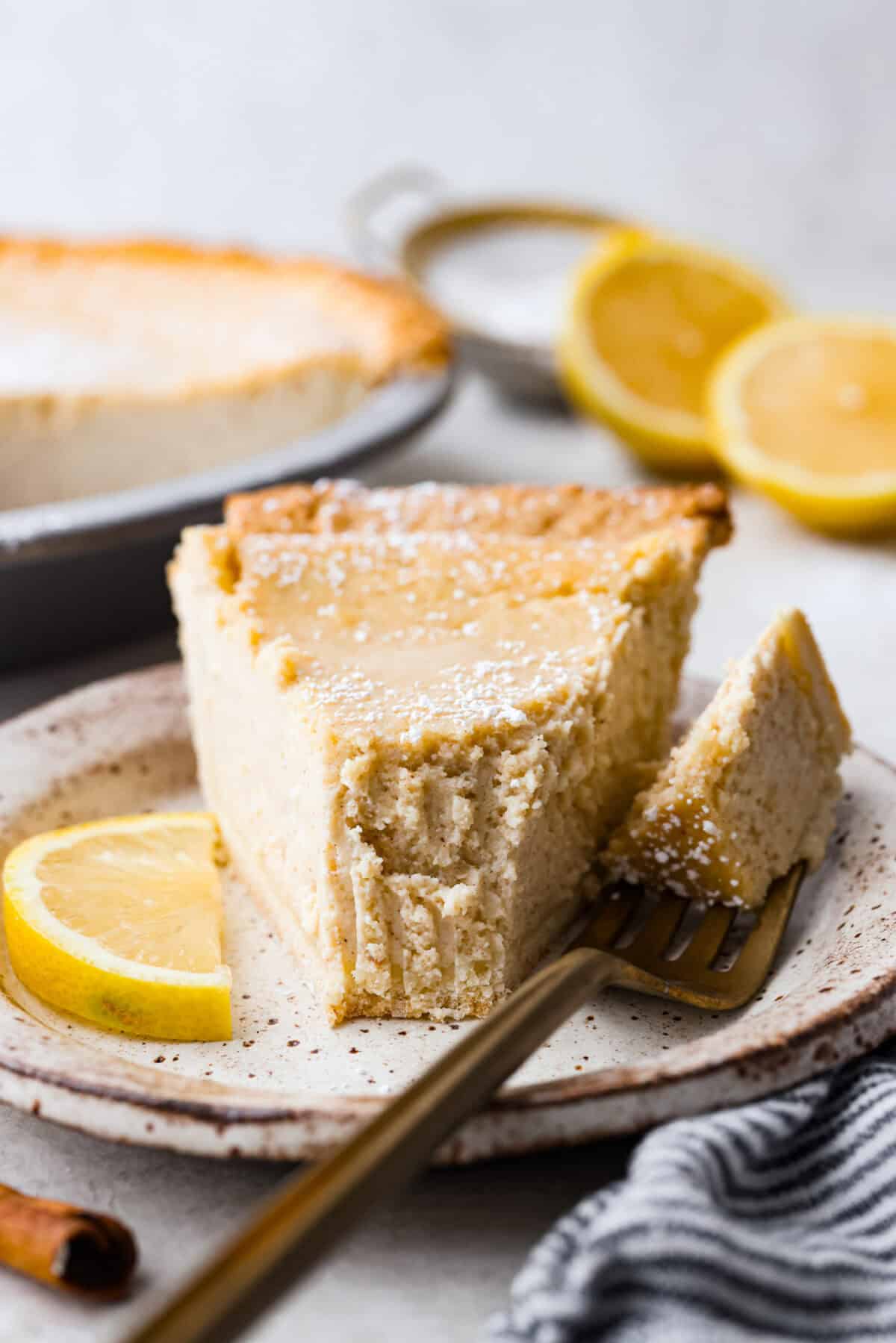 This creamy Ricotta Pie has a milky cinnamon flavor with a hint of lemon. The flavor is incredible, and it's surprisingly light for a cheese-based custard with its buttery shortbread crust. Close up shot of a plated piece of ricotta pie.