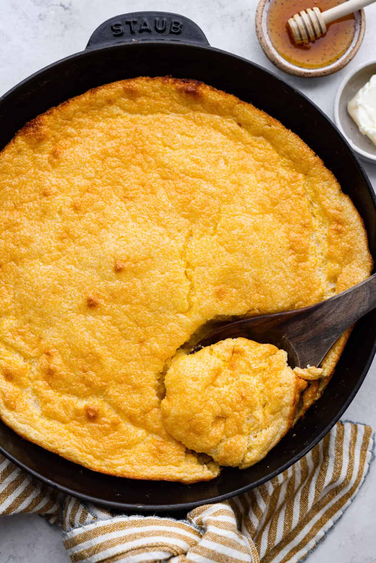 Spoon bread is a beloved classic Southern side dish. It’s similar to cornbread but is less sweet and has a softer, almost soufflé-like texture. This unique bread is best enjoyed warm with a dollop of butter, a drizzle of honey or served alongside a hearty bowl of chili. Overhead shot of spoon bread in a skillet.