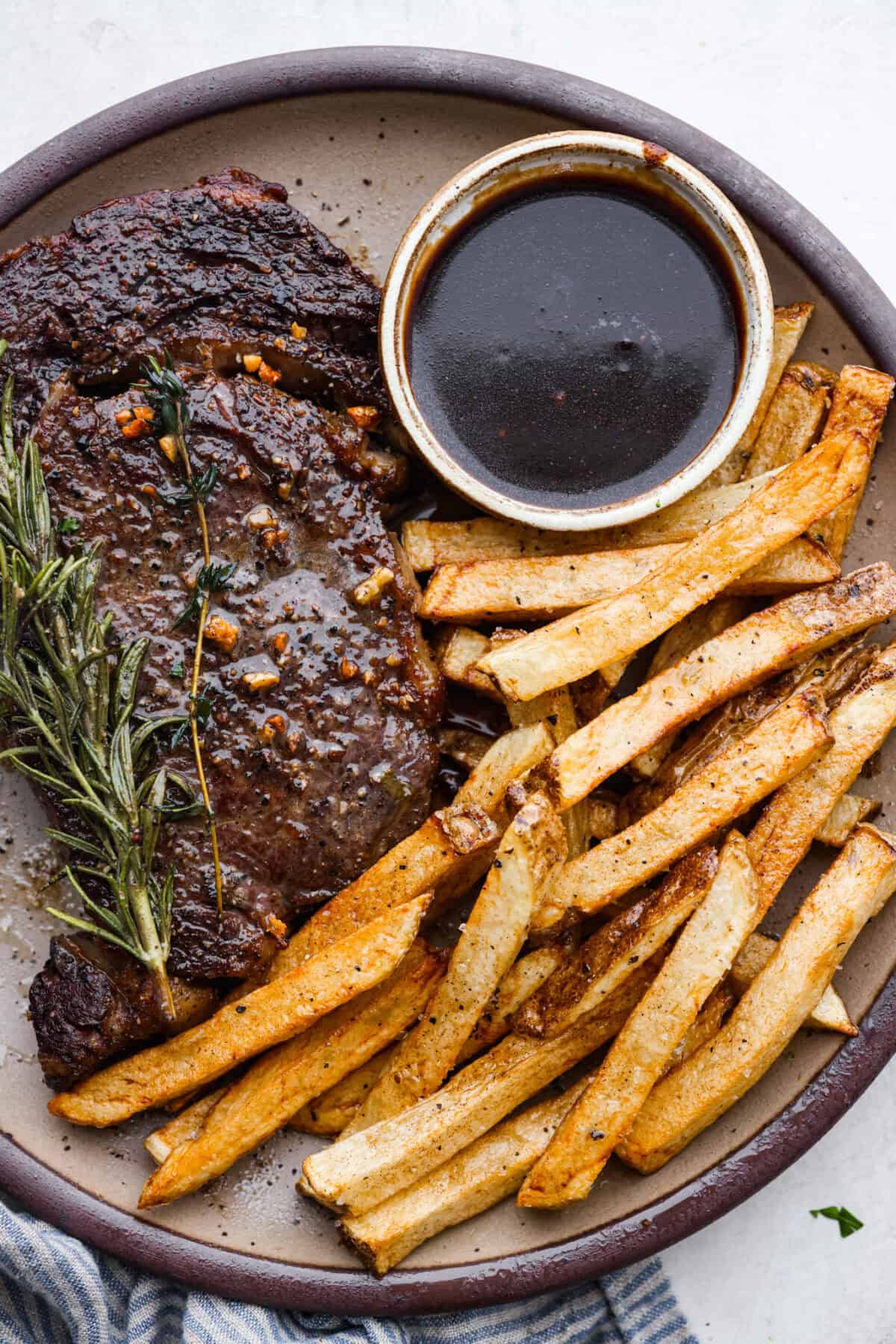 Steak Frites is a classic French bistro dish that combines perfectly seared, juicy steak with crispy, golden fries. It's a simple yet delicious meal that is filled with rich flavors and satisfying crunch. You will love this restaurant-quality dinner made right in your own kitchen! Overhead shot of plated steak frites.