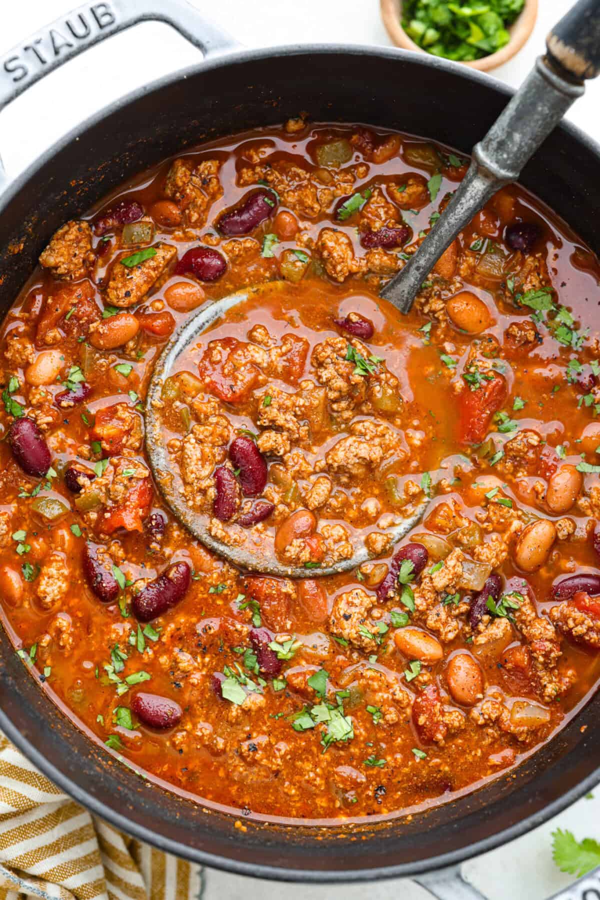 Turkey chili is such a comforting, satisfying meal! Packed with ground turkey, tender vegetables, hearty beans and a blend of bold spices, itโs filled with the most delicious flavor. Great for making ahead and feeding a crowd! Overhead shot of turkey chili in a pot.