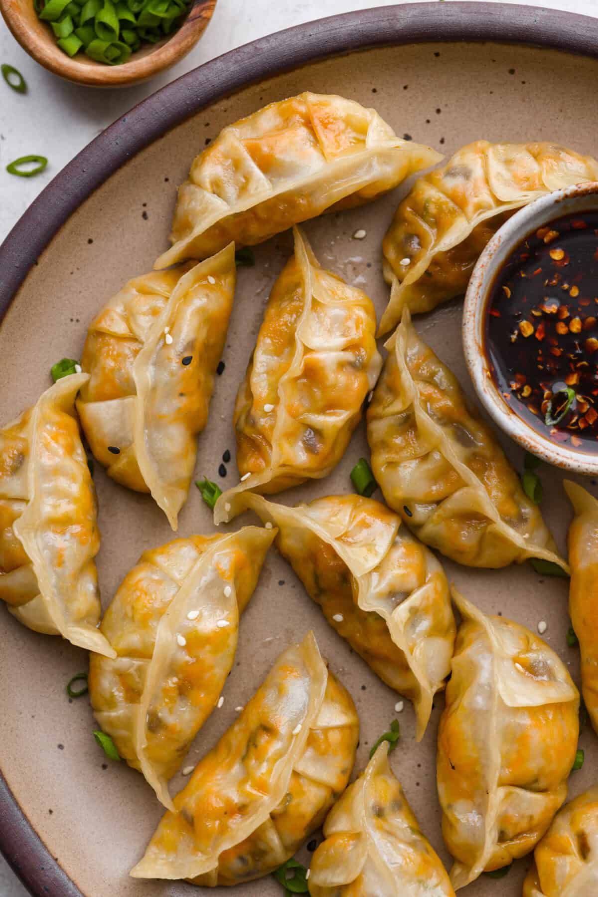 These vegetable dumplings are so full of Asian flavor, you won’t be able to stop at just one! Tender wontons are filled with an incredible veggie mixture that's infused with ginger, soy sauce, sesame oil and garlic. Like a potsticker without the meat! Overhead shot of the vegetable dumplings on a serving plate.