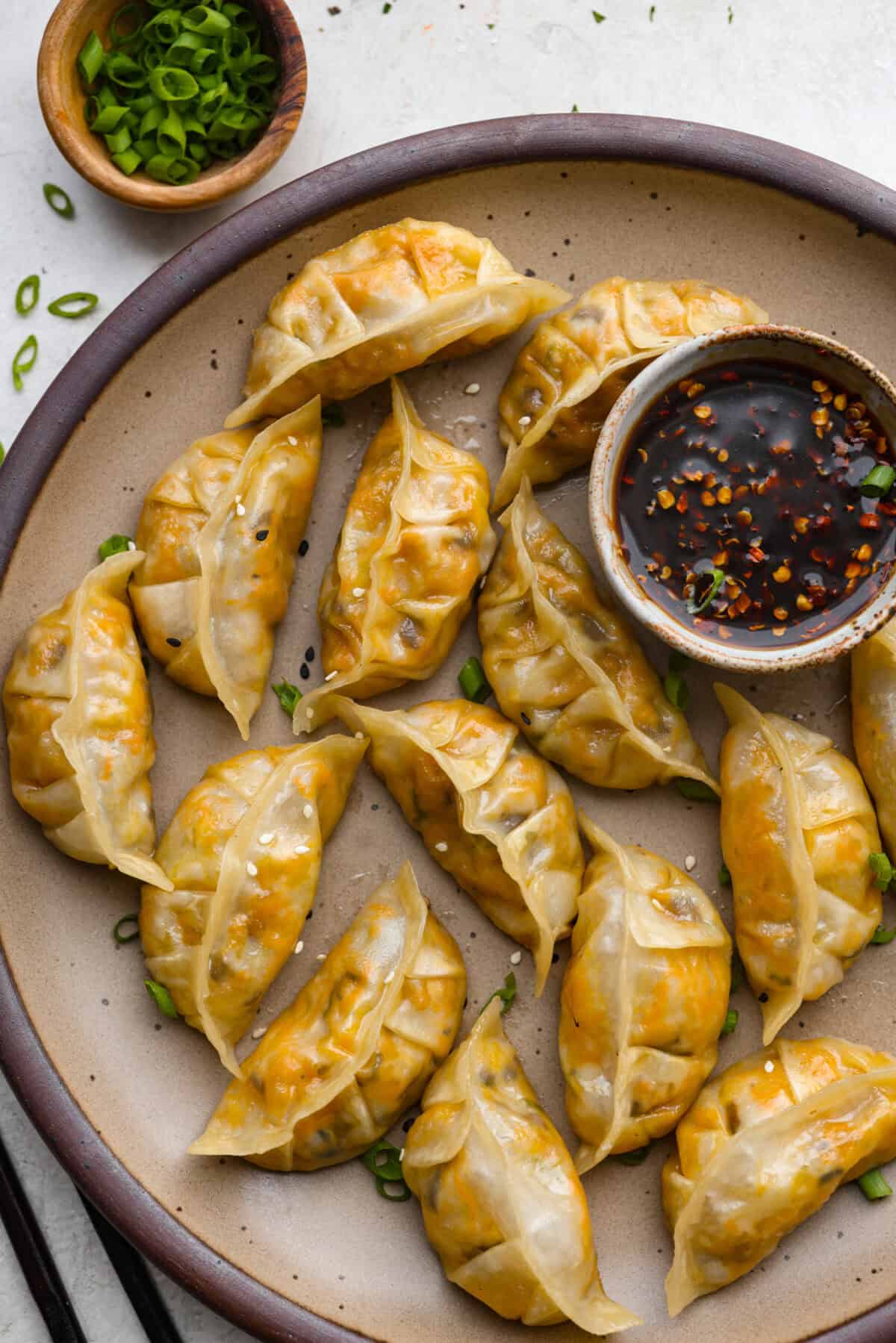These vegetable dumplings are so full of Asian flavor, you won’t be able to stop at just one! Tender wontons are filled with an incredible veggie mixture that's infused with ginger, soy sauce, sesame oil and garlic. Like a potsticker without the meat! Overhead shot of vegetbale dumplings on a serving plate.