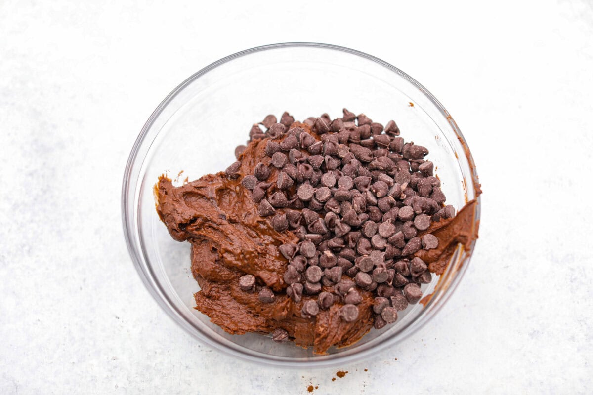 Black bean brownies are rich, fudgy, and packed with chocolatey goodness! They have a slightly denser texture, similar to a protein bar, but still satisfy that brownie craving. While adults may notice a slight difference from traditional brownies, kids wonโt be able to tell! Overhead shot of black bean brownie batter in a mixing bowl with chocolate chips added to it.
