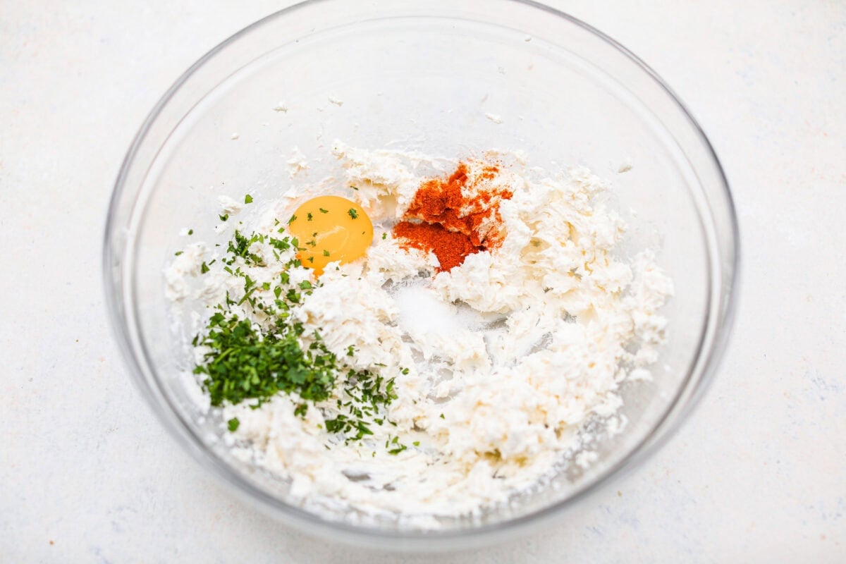 These Crab Stuffed Mushrooms are a deliciously savory appetizer, perfect for impressing guests at any gathering. With a rich crab filling in every bite, they’re sure to be a crowd favorite! Overhead shot of the whisked cream cheese with egg yolk, paprika and salt in a mixing bowl.