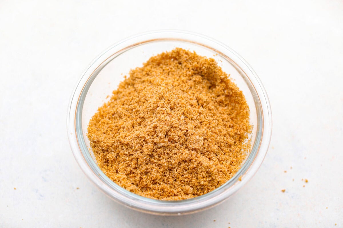 Creme Brulee Cheesecake is the perfect merging of two beloved desserts! It has the rich, creamy texture of cheesecake with the caramelized sugar topping of classic crรจme brรปlรฉe. This irresistible treat is the best of both worlds! Graham cracker crumbs in a small bowl.