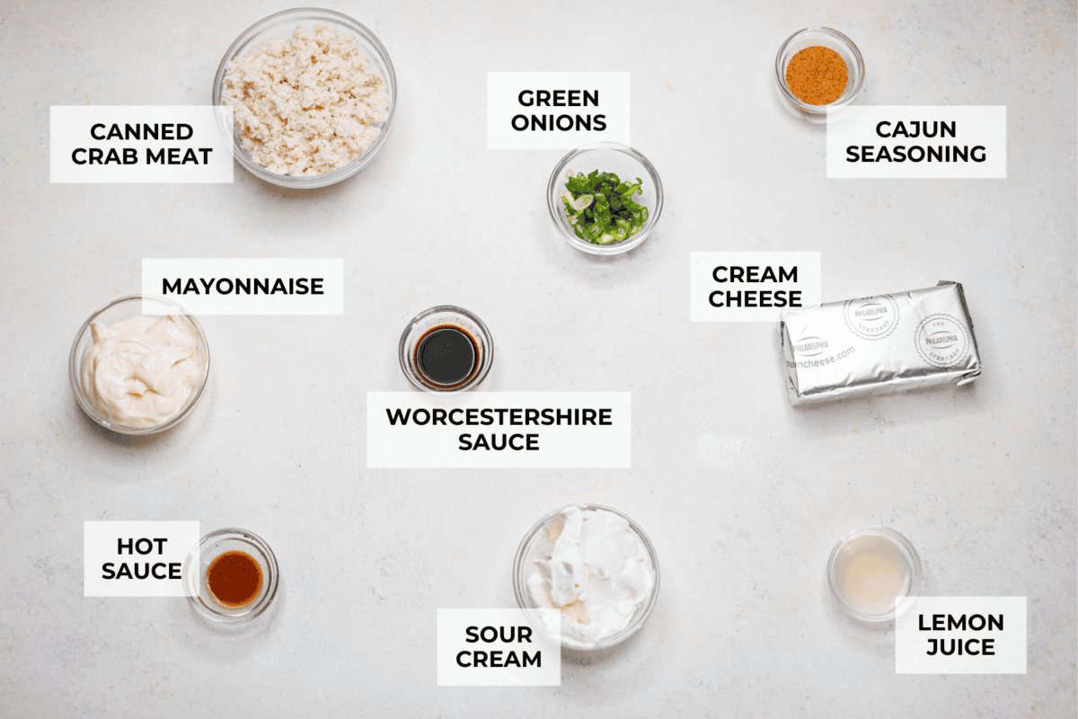 Spice up your appetizer game with Cajun Crab Dip! Packed with tender crab meat, bold Cajun seasoning, and a luscious, creamy base. This dip is irresistibly rich and full of flavor. Serve this at your next gathering with your favorite crispy crackers! Overhead shot of labeled cajun crab dip ingredients.