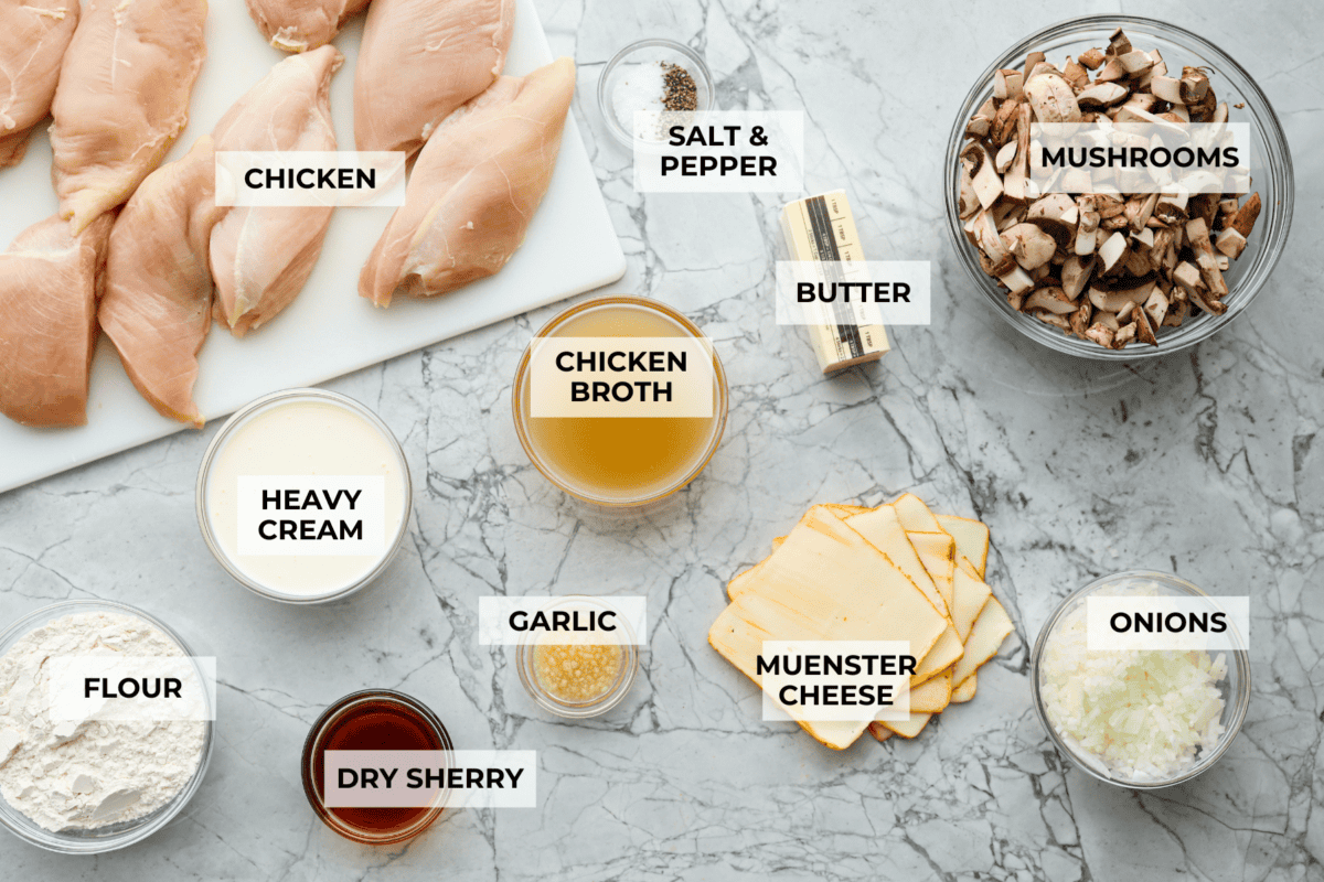 This Chicken Gloria is moist, perfectly baked chicken with a slightly seared crust. It cooks in a creamy sauce that is slightly tangy and full of flavor. It's topped with gooey cheese and makes a very satisfying meal! Overhead shot of labeled ingredients.