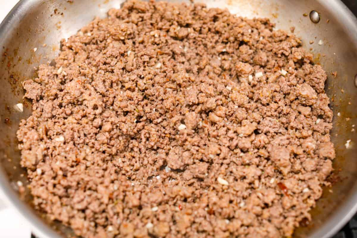 Million Dollar Baked Ziti is the ultimate comfort food that tastes like a million bucks! It's packed with layers of tender noodles, ground meat, spaghetti sauce, and plenty of cheesy goodness. There is something for the whole family in this hearty, crowd-pleasing dish! Overhead shot of garlic added to the cooked meat.