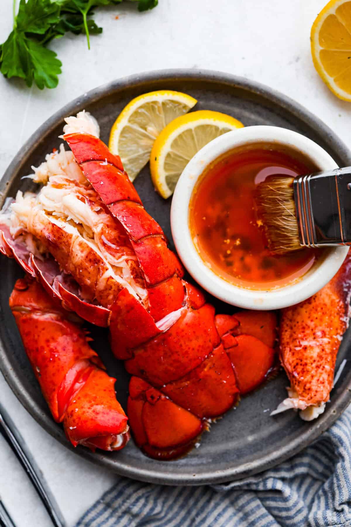 Learn how to boil lobster and enjoy this simple and delicious seafood delicacy. With a few basic steps, you'll have perfectly cooked, tender lobster in just 20 minutes! Serve it with melted butter and your favorite sides. Overhead shot of a lobster tail, meat from the claw and leg on a plate with a small bowl of melted butter.
