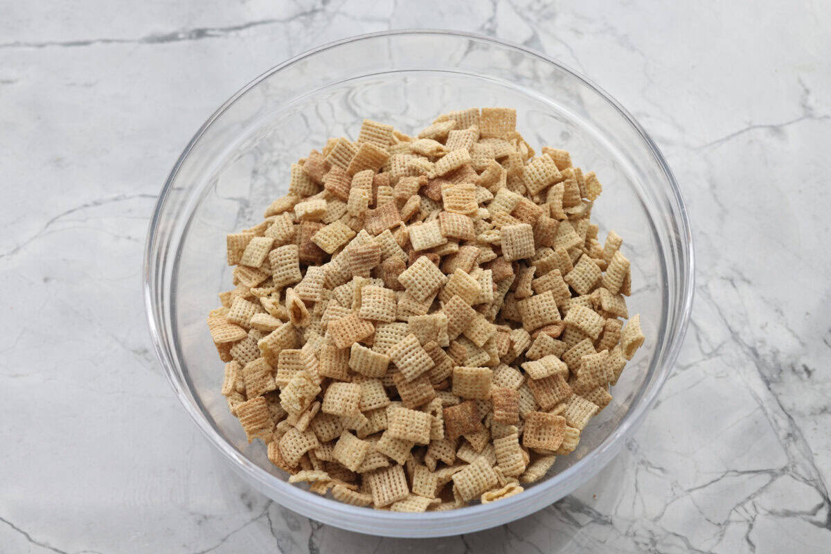 Churro Chex Mix is a fun variation of the popular muddy buddy mix. Sweet cinnamon and sugar mixed with silky white chocolate coat the crunchy cereal to create an addicting treat. It's the perfect snack to whip up for game day, road trips, or weeknights when that sweet tooth hits! Overhead shot of cereals mixed together in a large bowl.
