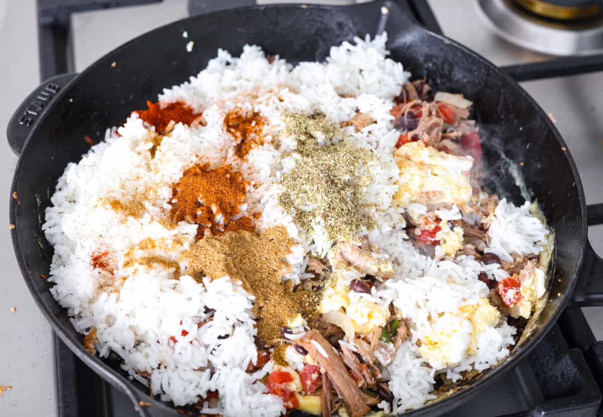 Cowboy Fried Rice is a Tex-Mex twist on the classic! It's loaded with bold spices and hearty ingredients like pulled pork, black beans, and diced tomatoes. Made in one skillet and ready in just 30 minutes, itโs the perfect quick and satisfying meal for busy nights. Overhead shot of pork and egg mixture with rice and seasonings added in.