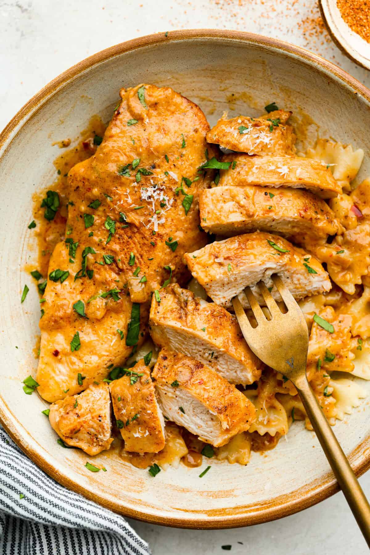 Creamy Cajun Chicken is the perfect combination of bold, zesty flavors and rich, velvety sauce. Juicy, tender chicken is coated in a perfectly spiced Cajun seasoning and simmered in a luscious, creamy sauce thatโs packed with flavor. Overhead shot of plated creamy cajun chicken over bowtie pasta.