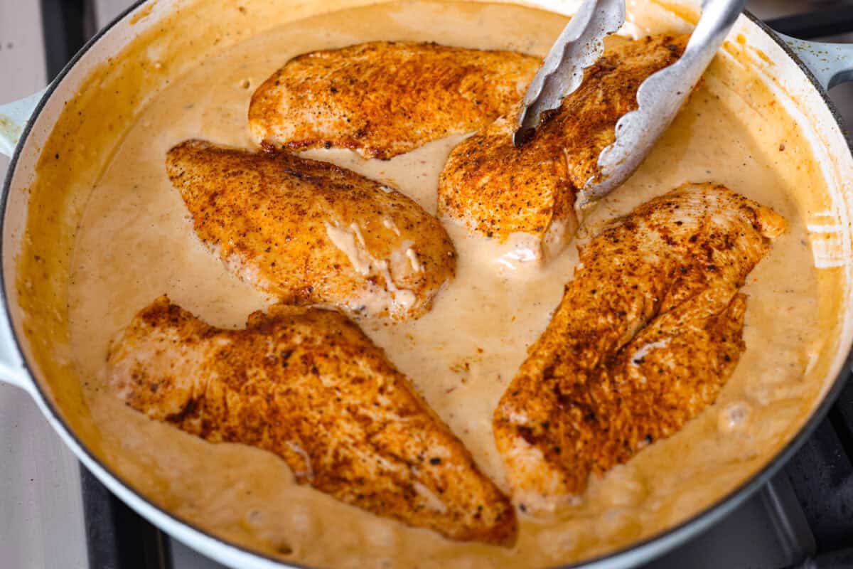 Creamy Cajun Chicken is the perfect combination of bold, zesty flavors and rich, velvety sauce. Juicy, tender chicken is coated in a perfectly spiced Cajun seasoning and simmered in a luscious, creamy sauce thatโs packed with flavor. Close up shot of the chicken being added back into the creamy cajun sauce.