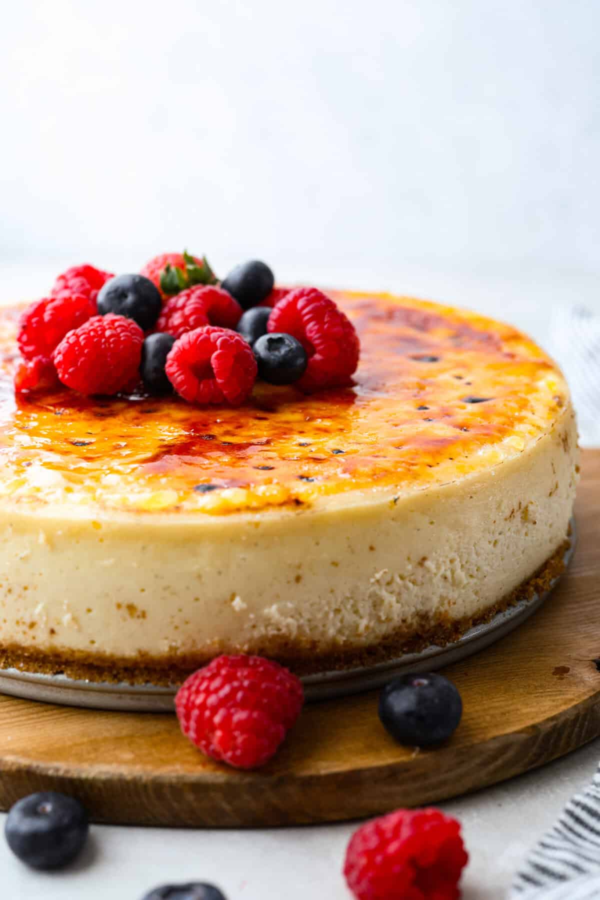 Creme Brulee Cheesecake is the perfect merging of two beloved desserts! It has the rich, creamy texture of cheesecake with the caramelized sugar topping of classic crรจme brรปlรฉe. This irresistible treat is the best of both worlds! Creme brรปlรฉe cheesecake with fresh raspberries and blueberries on top.