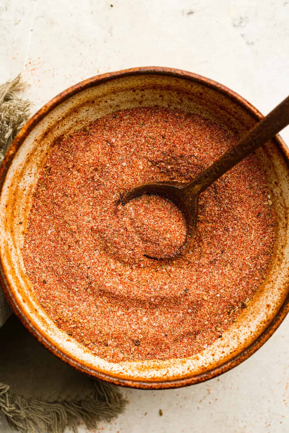 Creole seasoning is a bold and flavorful spice blend that brings the lively taste of Louisiana to your kitchen! It has the perfect balance of herbs, spices, and a touch of heat. It adds depth to everything from gumbo and jambalaya to roasted veggies and seafood. Overhead shot of creole seasoning in a bowl with a small wooden spoon.